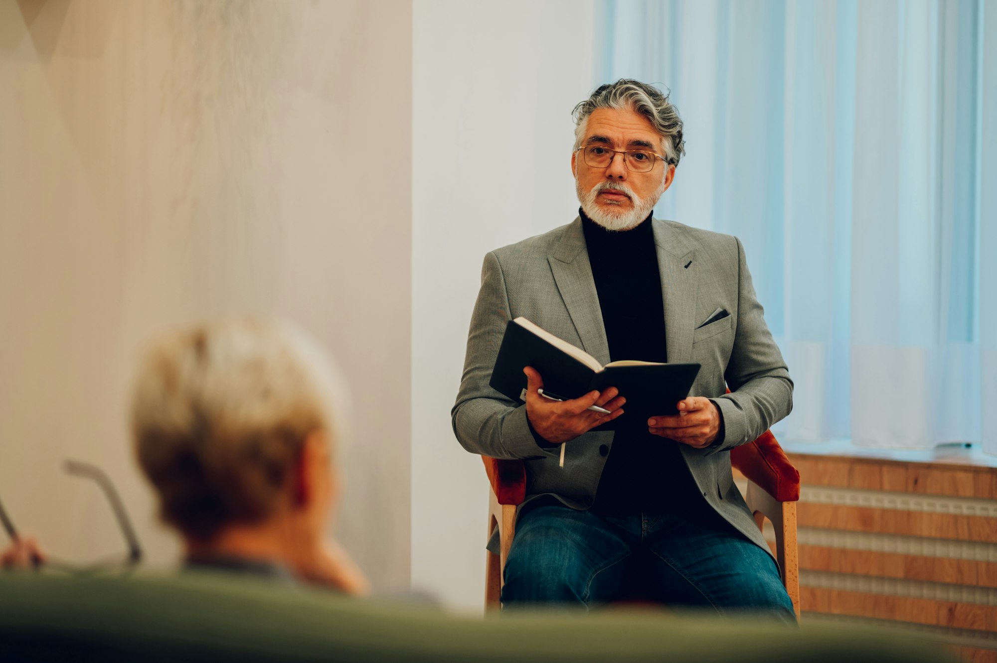 A psychotherapist is sitting with a textbook in his hands.