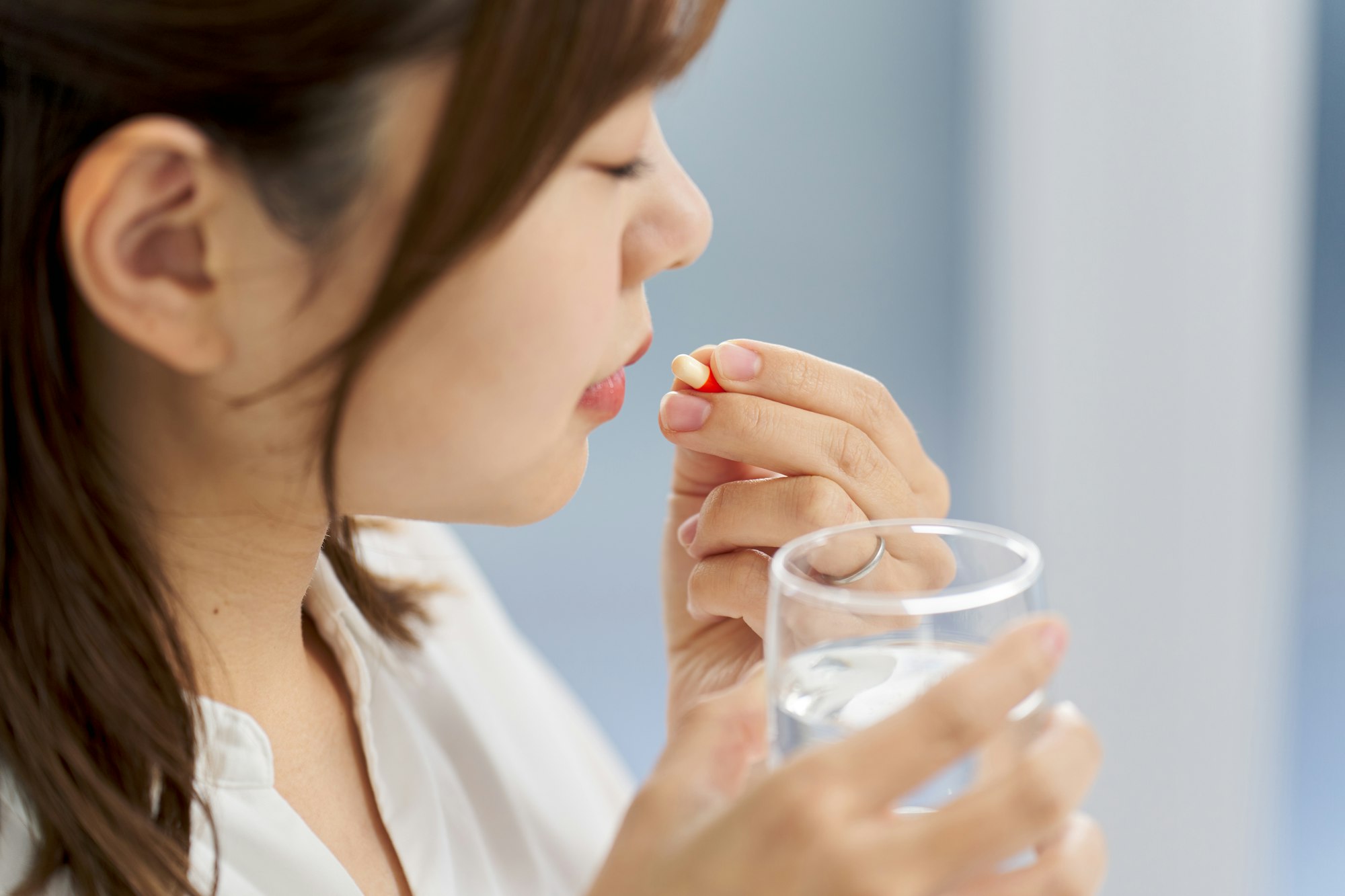 Asian woman drinking capsule medicine