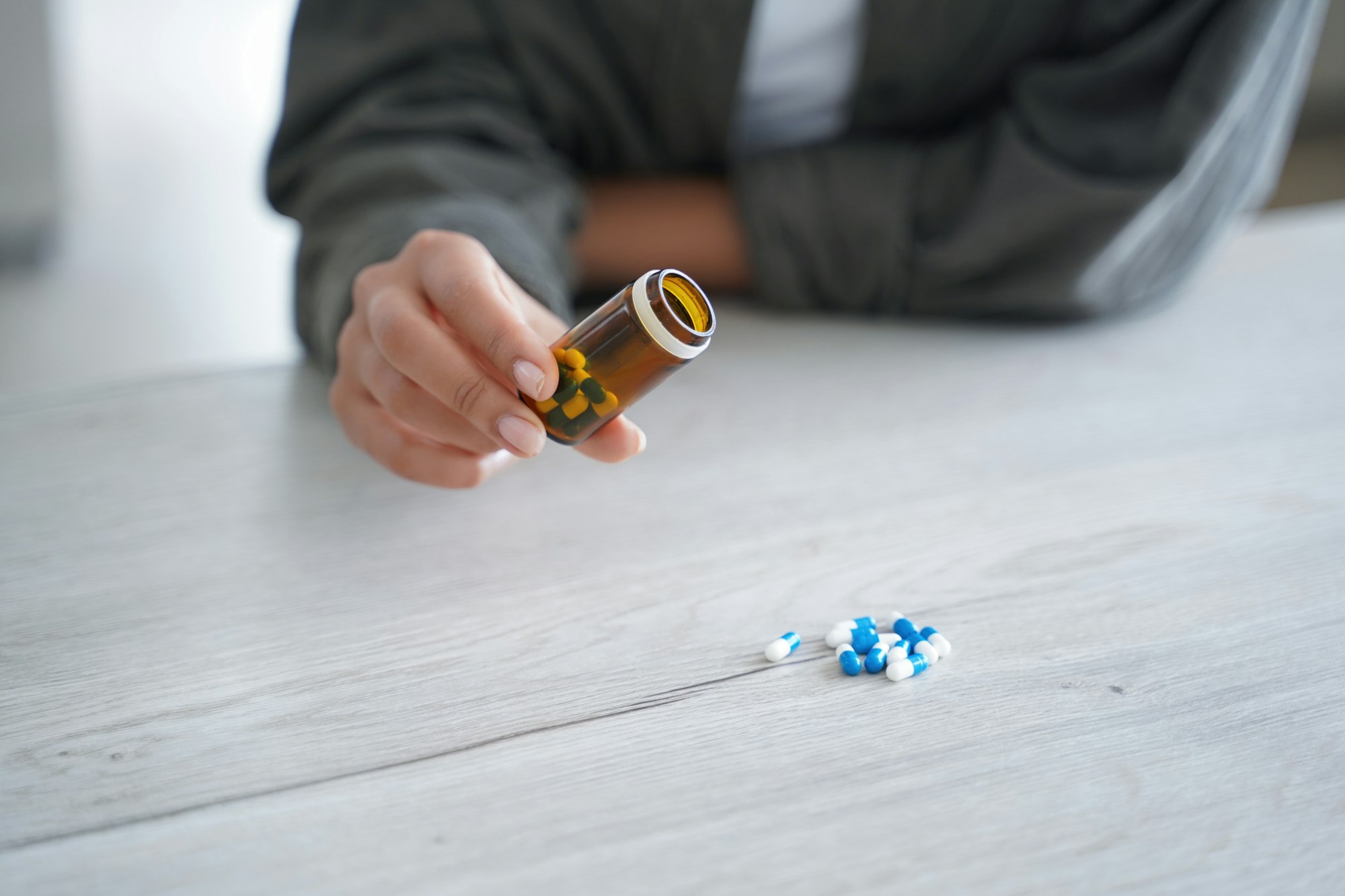 Female holds jar with medicines, pours pills on table, close up. Dietary supplement, vitamins, meds