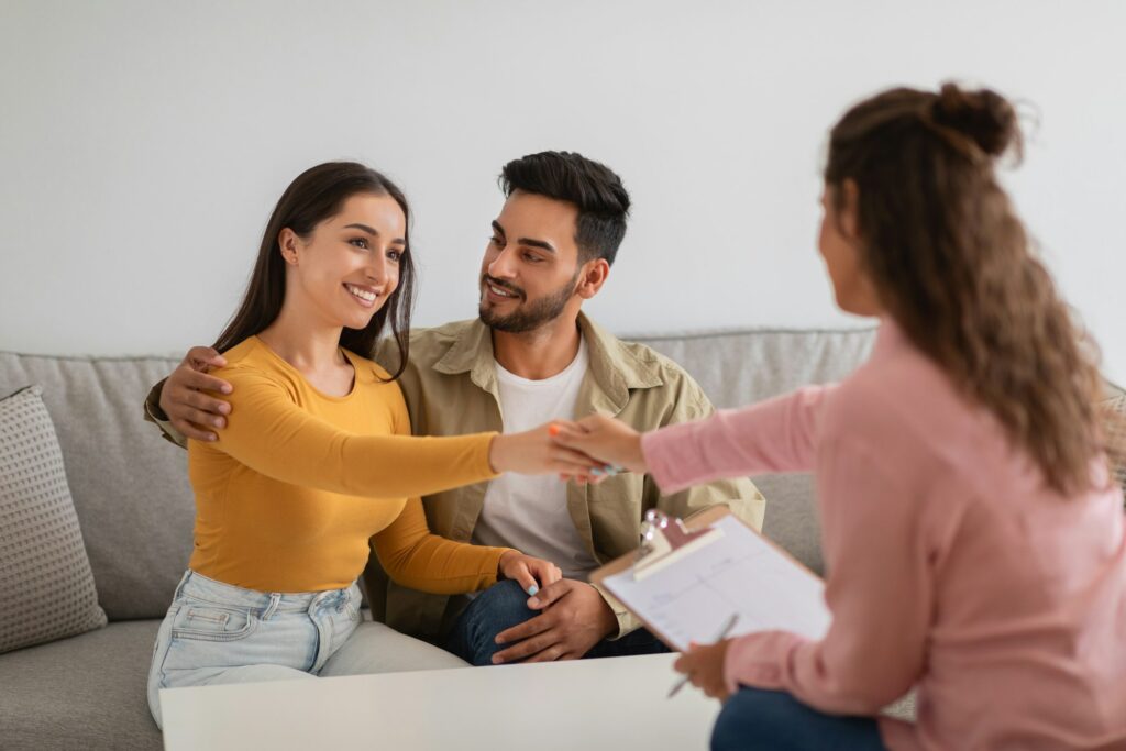 Couple shaking hands with a professional woman