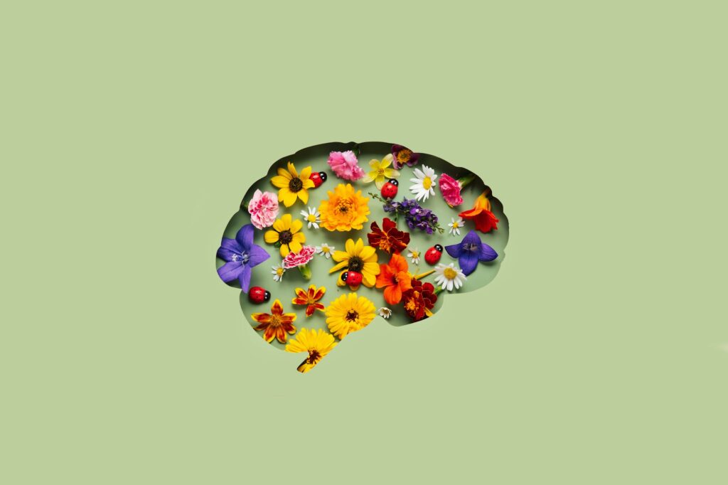 Paper cut brain symbol and flowers on green background