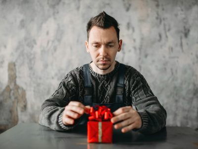 Autist man sitting against gift in wrapping paper