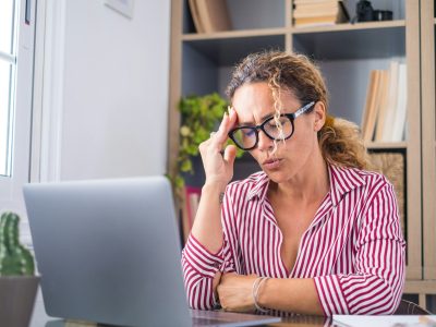 Unhealthy stressed businesswoman taking off eyeglasses, rubbing eyelids, suffering from dry eyes